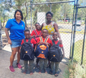family with children smiling holding new backpacks
