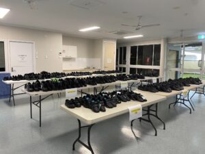 Rows of shoes on tables in community centre room